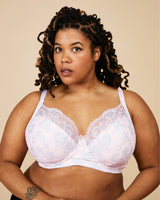 Woman wearing a white lace bra against a beige background. This bra is the Willowdale Bra sewing pattern from Cashmerette.
