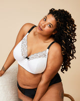 Woman wearing a white bra with lace details and black underwear on a beige background. This bra is the Willowdale Bra sewing pattern from Cashmerette.