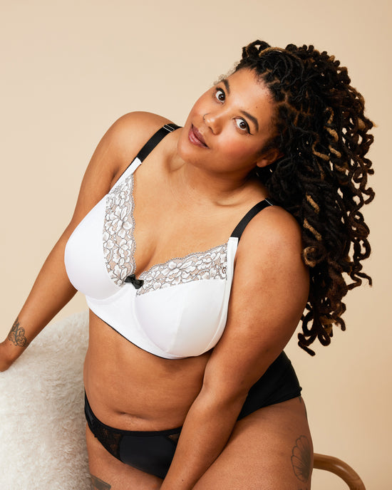 Woman wearing a white bra with lace details and black underwear on a beige background. This bra is the Willowdale Bra sewing pattern from Cashmerette.