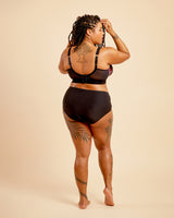 Person wearing a black bikini set on a beige background. This bralette is the Loftus Bralette sewing pattern from Cashmerette.