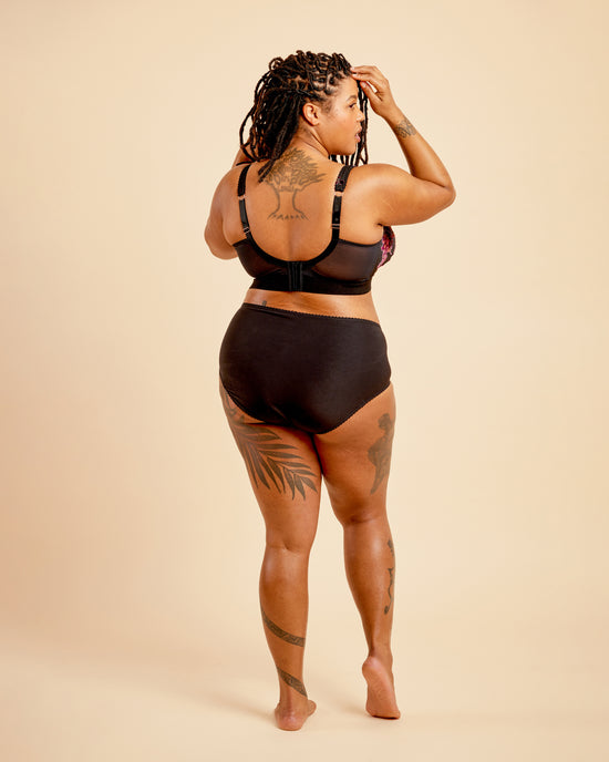 Person wearing a black bikini set on a beige background. This bralette is the Loftus Bralette sewing pattern from Cashmerette.