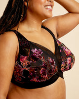 Woman wearing a floral black bralette against a beige background. This bralette is the Loftus Bralette sewing pattern from Cashmerette.