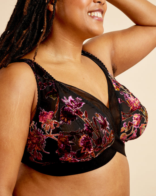 Woman wearing a floral black bralette against a beige background. This bralette is the Loftus Bralette sewing pattern from Cashmerette.