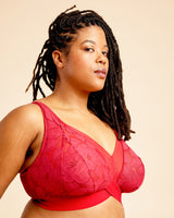 Woman wearing a red lace bralette against a beige background. This bralette is the Loftus Bralette sewing pattern from Cashmerette.