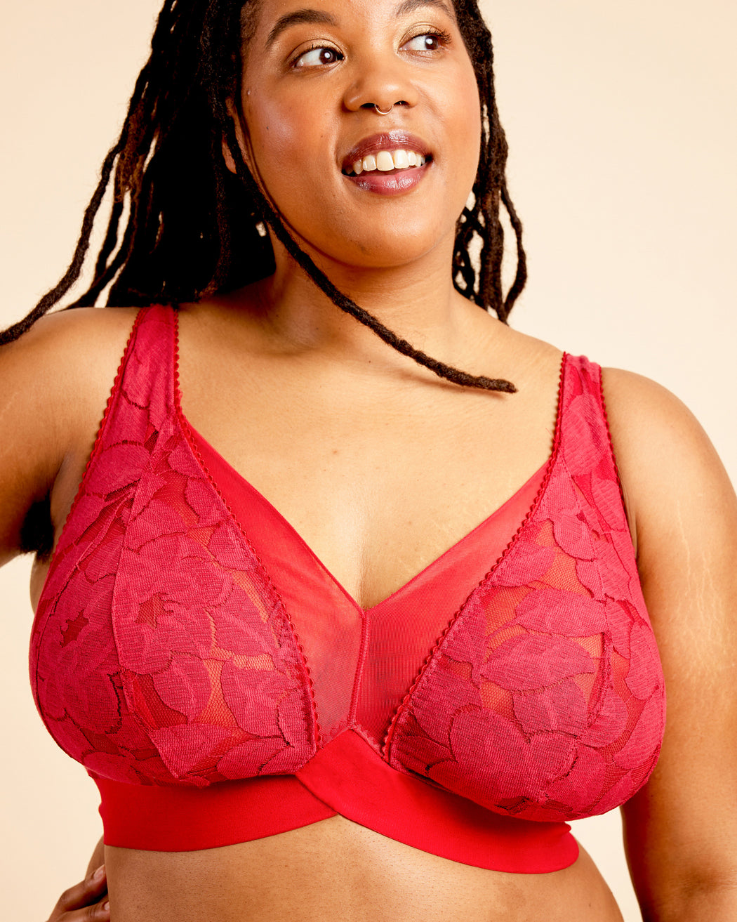 Woman wearing a red lace bra against a beige background. This bralette is the Loftus Bralette sewing pattern from Cashmerette.