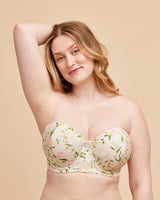 Woman wearing a floral strapless bra against a beige background. This bra is the Symmes Strapless Bra sewing pattern from Cashmerette.