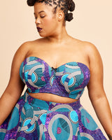 Woman wearing a strapless top and skirt with a purple and blue pattern on a beige background. This bra is the Symmes Strapless Bra sewing pattern from Cashmerette.