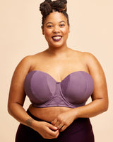 Woman wearing a purple strapless top against a beige background. This bra is the Symmes Strapless Bra sewing pattern from Cashmerette.