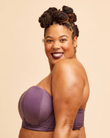 Woman wearing a purple strapless top against a beige background. This bra is the Symmes Strapless Bra sewing pattern from Cashmerette.