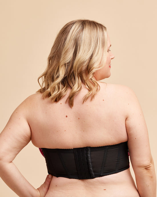 Woman wearing a black strapless top against a beige background. This bra is the Symmes Strapless Bra sewing pattern from Cashmerette.