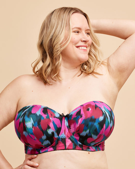 Woman wearing a colorful strapless top against a beige background. This bra is the Symmes Strapless Bra sewing pattern from Cashmerette.
