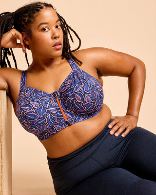 Woman wearing a blue patterned sports bra and navy leggings against a beige background. This is the Somerville Sports Bra sewing pattern from Cashmerette.