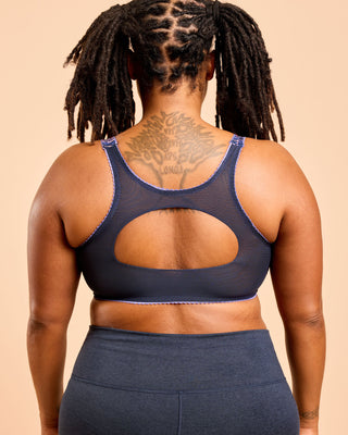 Person wearing a navy blue sports bra and leggings on a beige background. This is the Cashmerette Somerville Sports Bra sewing pattern for big boobs.