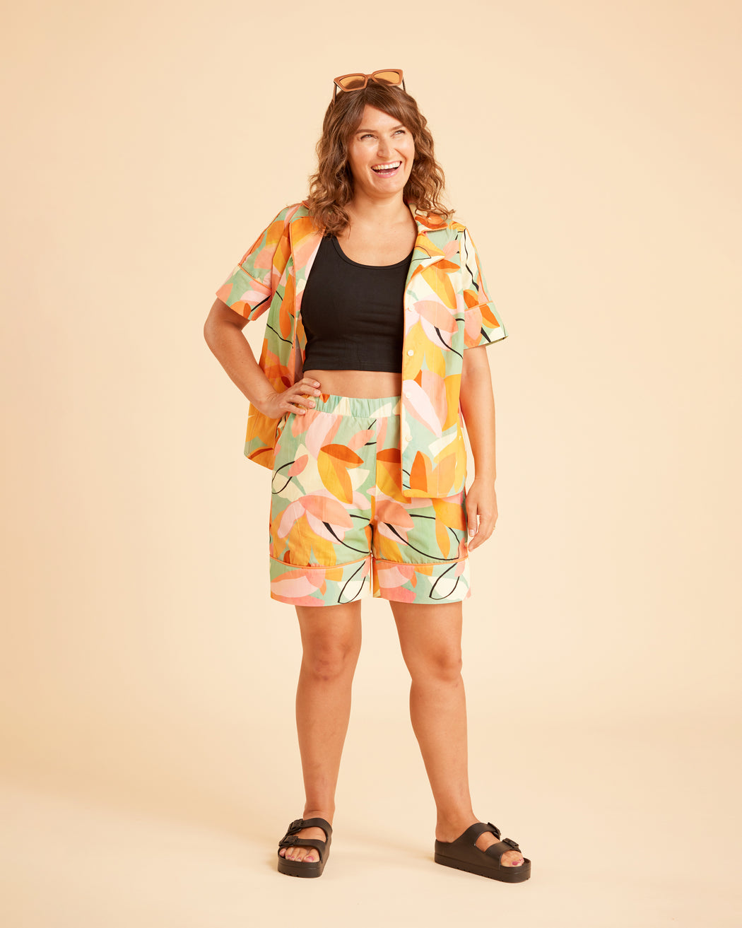 Woman wearing a colorful outfit with a patterned jacket and shorts on a beige background. This is the Fiske Sleepwear Set sewing pattern from Cashmerette.