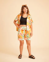 Woman wearing a colorful outfit with a patterned jacket and shorts on a beige background. This is the Fiske Sleepwear Set sewing pattern from Cashmerette.