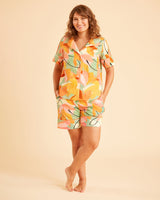 Woman wearing a colorful floral dress on a beige background. This is the Fiske Sleepwear Set sewing pattern from Cashmerette.
