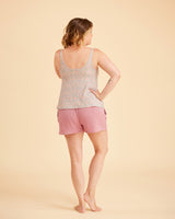 Woman wearing a patterned tank top and pink shorts on a beige background. This is the Fiske Sleepwear Set sewing pattern from Cashmerette.