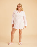 Woman wearing a light pink nightshirt on a beige background. This is the Fiske Sleepwear Set sewing pattern from Cashmerette.