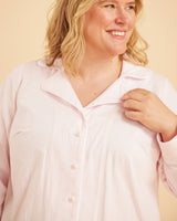 Woman wearing a light pink shirt against a beige background. This is the Fiske Sleepwear Set sewing pattern from Cashmerette.