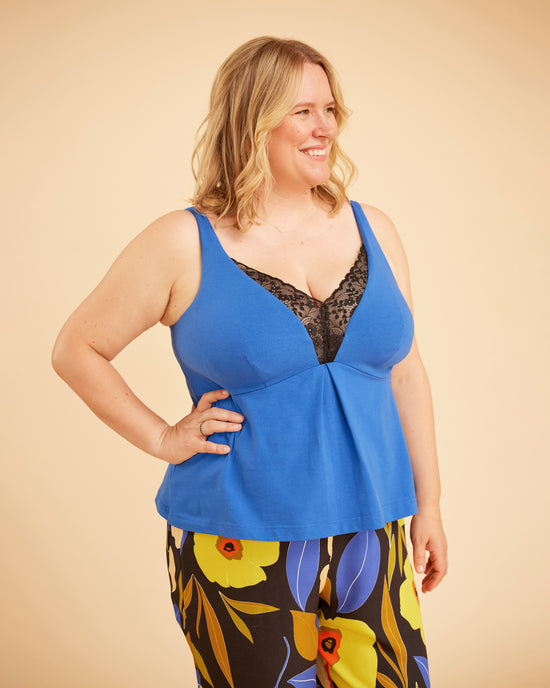 Woman wearing a blue top with floral pants on a beige background. This is the Fiske Sleepwear Set sewing pattern from Cashmerette.