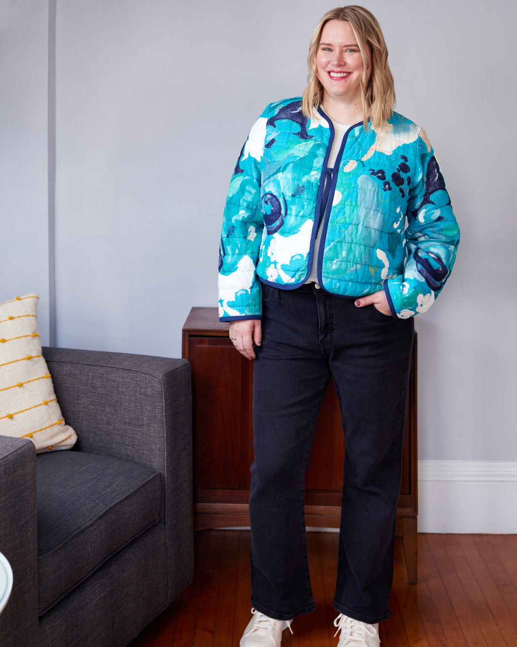 Person wearing a colorful jacket in a living room setting. This jacket is the Fairfax Quilted Jacket sewing pattern from "Sewing the Curve" by Jenny Rushmore.