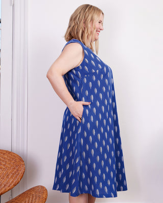 Woman wearing a blue dress with white patterns against a white wall. This dress is the Montvale Dress & Tunic sewing pattern from "Sewing the Curve" by Jenny Rushmore.