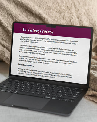 Laptop displaying a document titled 'The Fitting Process' on a textured surface.