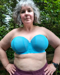 Person wearing a blue strapless bra outdoors with greenery in the background. This is the Symmes Strapless Bra sewing pattern from Cashmerette.