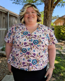 Woman wearing a floral blouse standing outdoors with trees and a house in the background. This is the Inman Top & Dress sewing pattern from Cashmerette.
